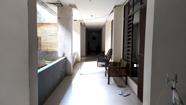 A narrow corridor with a bench and a pair of slippers on the floor. - Hotel O Batu Putih Homestay (Makassar)