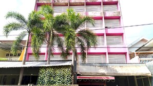 A multi-story building with a pink facade and a balcony. - Hotel O Batu Putih Homestay (Makassar)