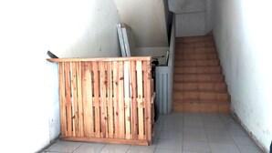 A narrow hallway with a wooden partition, a staircase, and a white wall. - Hotel O Batu Putih Homestay (Makassar)