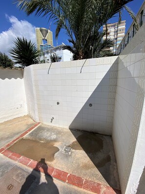 outdoor space with a tiled floor, drainage grate, and metal faucet, surrounded by a decorative wall and red brick border.