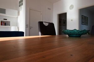 Un comedor con una mesa de madera, una silla negra, un cuenco de vidrio verde y una puerta blanca.