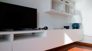 A modern living room with a flat-screen TV on a white entertainment unit, a lamp, and a blue decorative bowl. - Marechiare Intera in Ortona (Ortona)