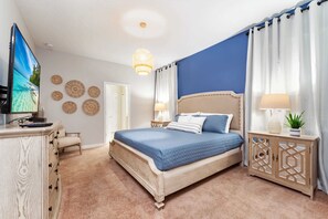 A bedroom with a bed, a TV, a dresser, and a nightstand.