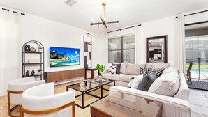 Un salon moderne comprenant un canapé, deux fauteuils, une table basse et un téléviseur.
