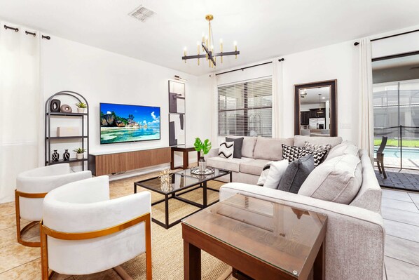 A modern living room with a sofa, two armchairs, a coffee table, and a TV.
