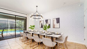 Un espace repas comprenant une longue table, des chaises et un lustre.