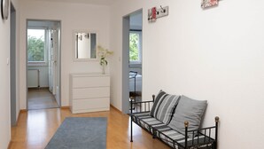 Una sala moderna con un sofá, un aparador blanco y un espejo. Hay dos puertas que dan a otras habitaciones.