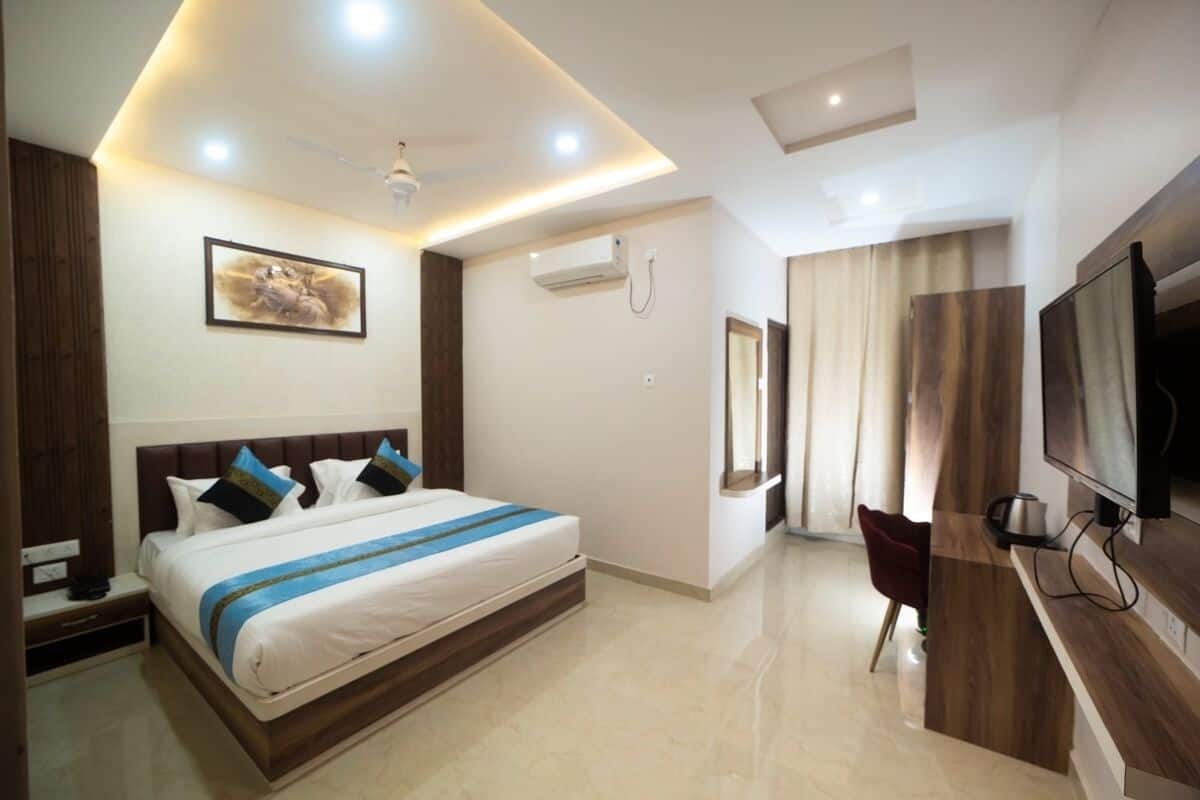 A modern hotel room with a large bed, a desk, a television, and a ceiling fan.