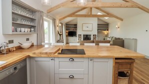 A modern kitchen with a wooden island, grey cabinets, and pendant lighting. - Cotswold View (Witney)