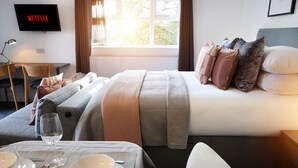 A neatly arranged hotel room with a bed, bedside table, and a TV displaying 'NETFLIX'. - The Woden Boutique Hotel Walsall M6 J9 (Wednesbury)
