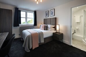 Ein modernes Schlafzimmer mit Bett, Nachttischen, einem Schreibtisch und einer Duschkabine.