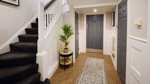A staircase with a potted plant, a rug, and a door in a hallway. - The Woden Boutique Hotel Walsall M6 J9 (Wednesbury)