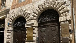 Un edificio con due imponenti porte decorate e una facciata in pietra.