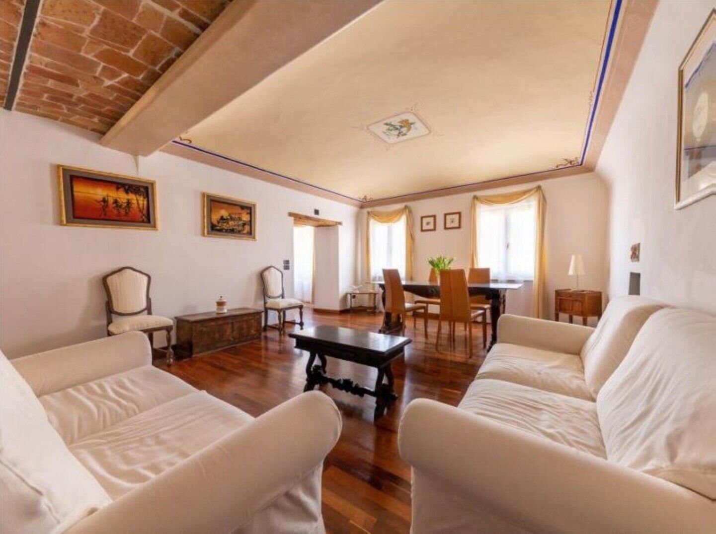 Un ampio soggiorno con zona pranzo, caratterizzato da un caminetto, pavimento in legno e soffitto alto.
