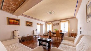 Un ampio soggiorno con zona pranzo, caratterizzato da un caminetto, pavimento in legno e soffitto alto.