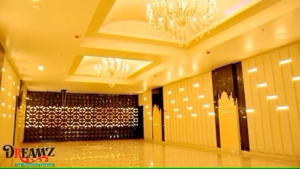 A spacious room with a high ceiling, decorative chandeliers, and a patterned wall. - Hotel Suncity  (Hisar)