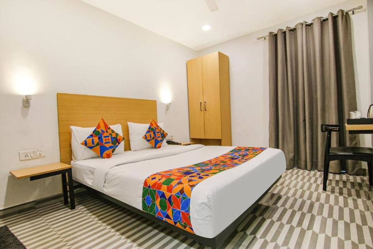 Ein Hotelzimmer mit einem Bett, einem Holzschrank, einem Schreibtisch mit Stuhl und einem karierten Boden.