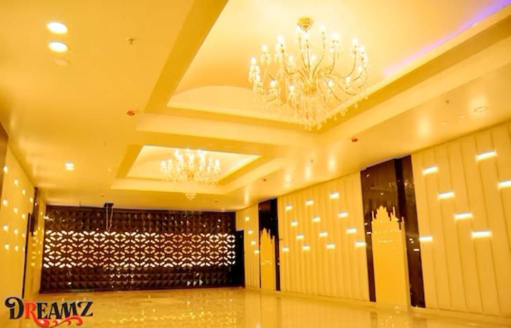 Ruime kamer met een hoog plafond, decoratieve kroonluchters en een patroonwand.
