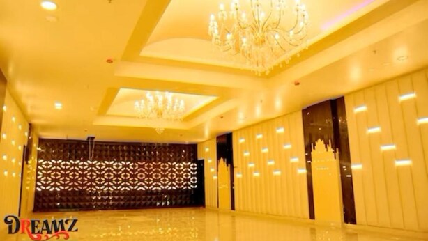 A spacious room with a high ceiling, decorative chandeliers, and a patterned wall. - Hotel Suncity  (Hisar)