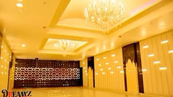 A spacious room with a high ceiling, decorative chandeliers, and a patterned wall.