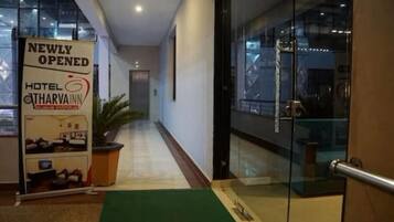 A hotel entrance with a 'Newly Opened' sign, a reception desk, and a potted plant.