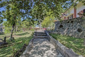 Un chemin de pierres menant à un bâtiment doté d’un mur en pierre et d’un drapeau.