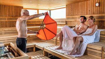 A sauna with wooden benches and benches, a towel rack, and a clock on the wall.