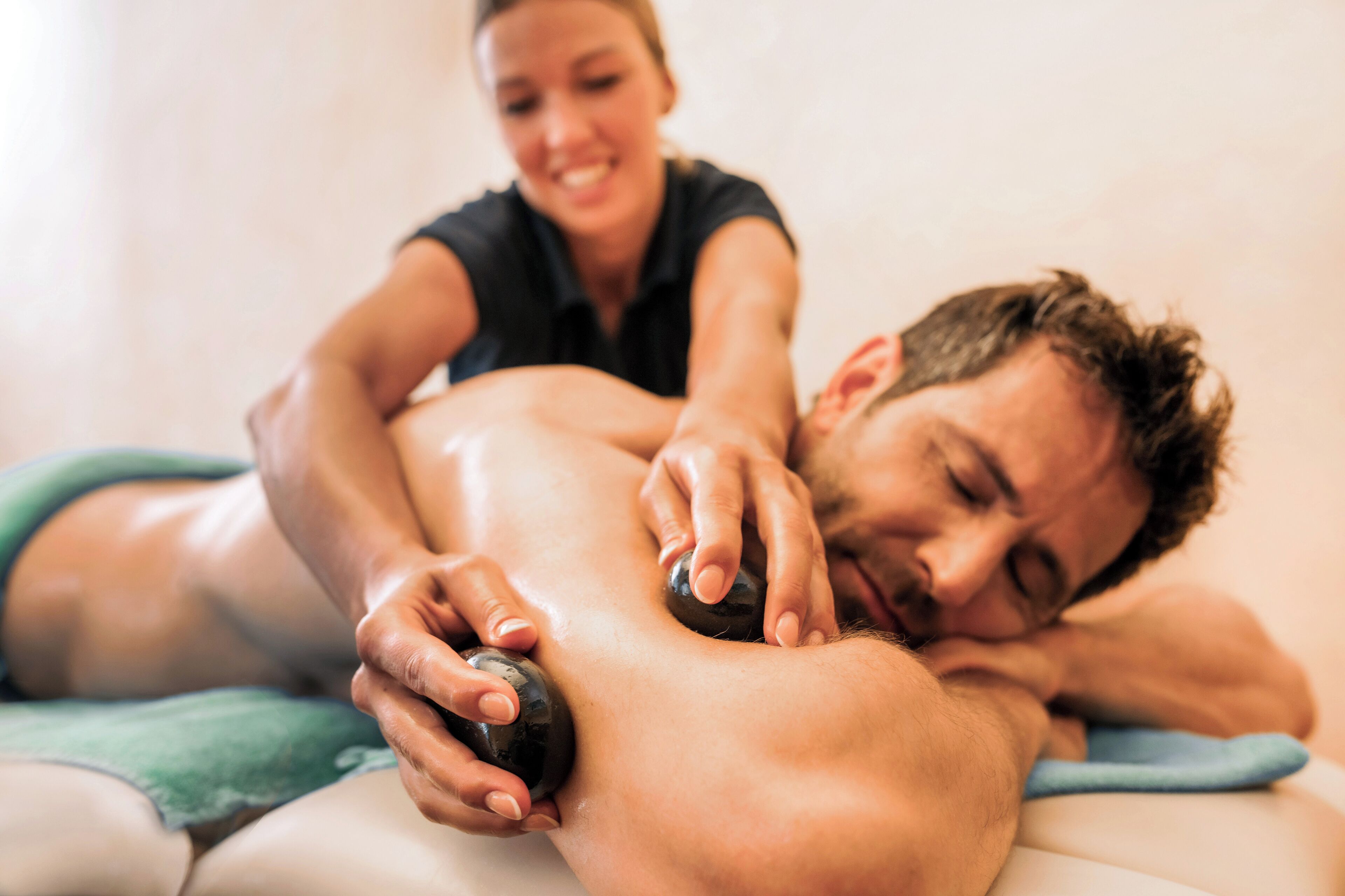 Eine Person erhält eine Massage, wobei der Therapeut einen Massagestein benutzt.