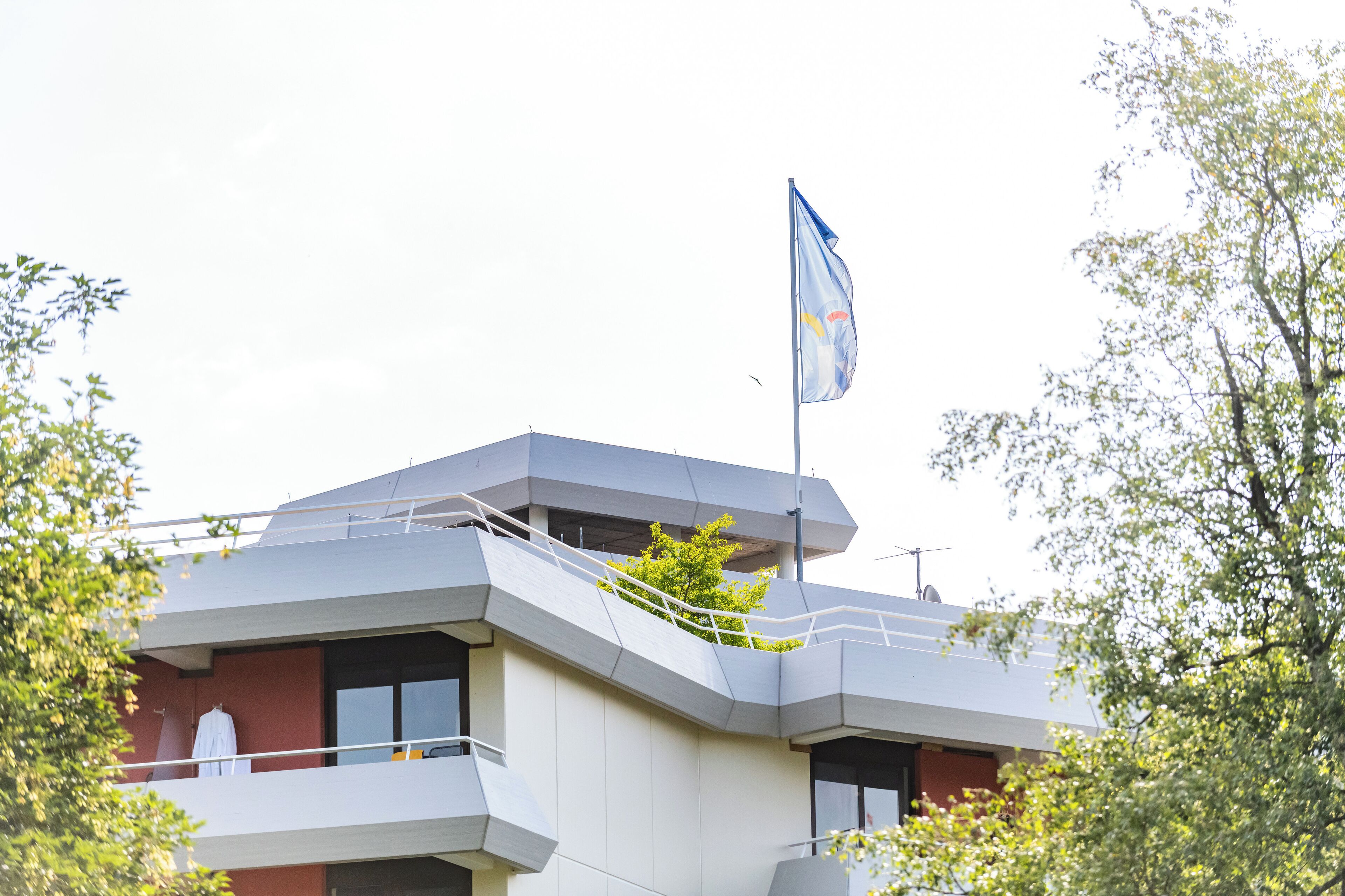 Un edificio moderno con una bandiera in cima, un balcone e una scala.