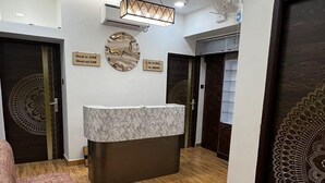 Un espace d’accueil d’hôtel doté d’un comptoir en marbre, d’un plancher en bois et de murs à motifs.