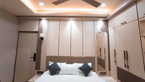 Une chambre à coucher comprenant un lit, un ventilateur de plafond, une armoire et un luminaire fixé au mur.
