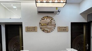 Un comptoir d’accueil avec un plateau en marbre, une horloge et des panneaux indiquant les heures d’arrivée et de départ, ainsi que les règles interdisant la consommation d’alcool et le tabagisme.