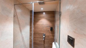 Une douche moderne dotée d’une porte en verre, de lambris en bois et d’un porte-serviettes apparent.