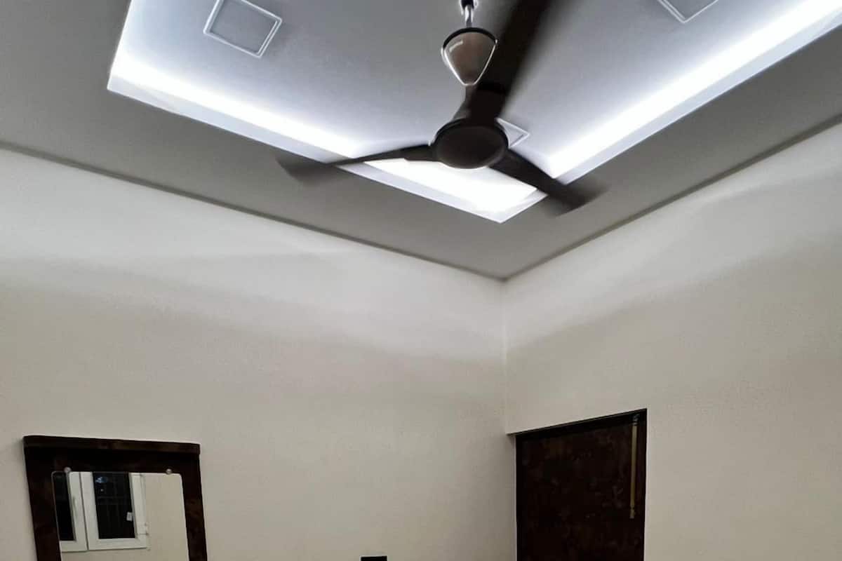 A bedroom with a bed, a ceiling fan, a mirror, and a wardrobe.