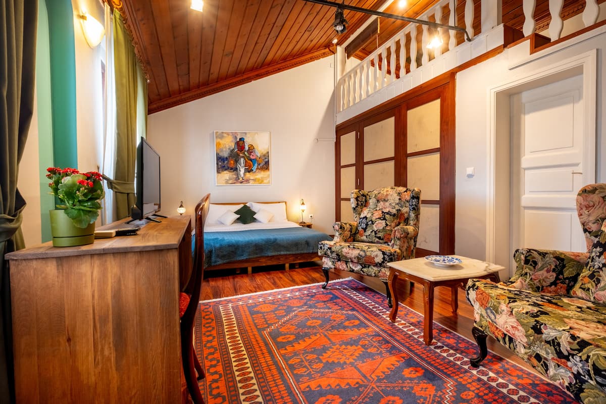 A cozy room with a bed, a chair, a table, and a TV.