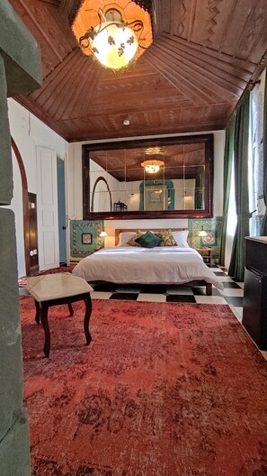 A bedroom with a bed, a nightstand, a chair, a mirror, and a chandelier. - Nevalist Hotel (Istanbul)