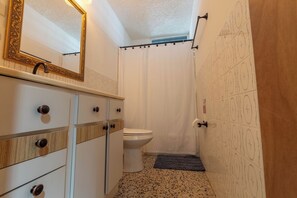 A bathroom with a white sink, mirror, and toilet.