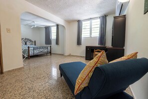 A room with a bed, a desk, a chair, and a sofa.