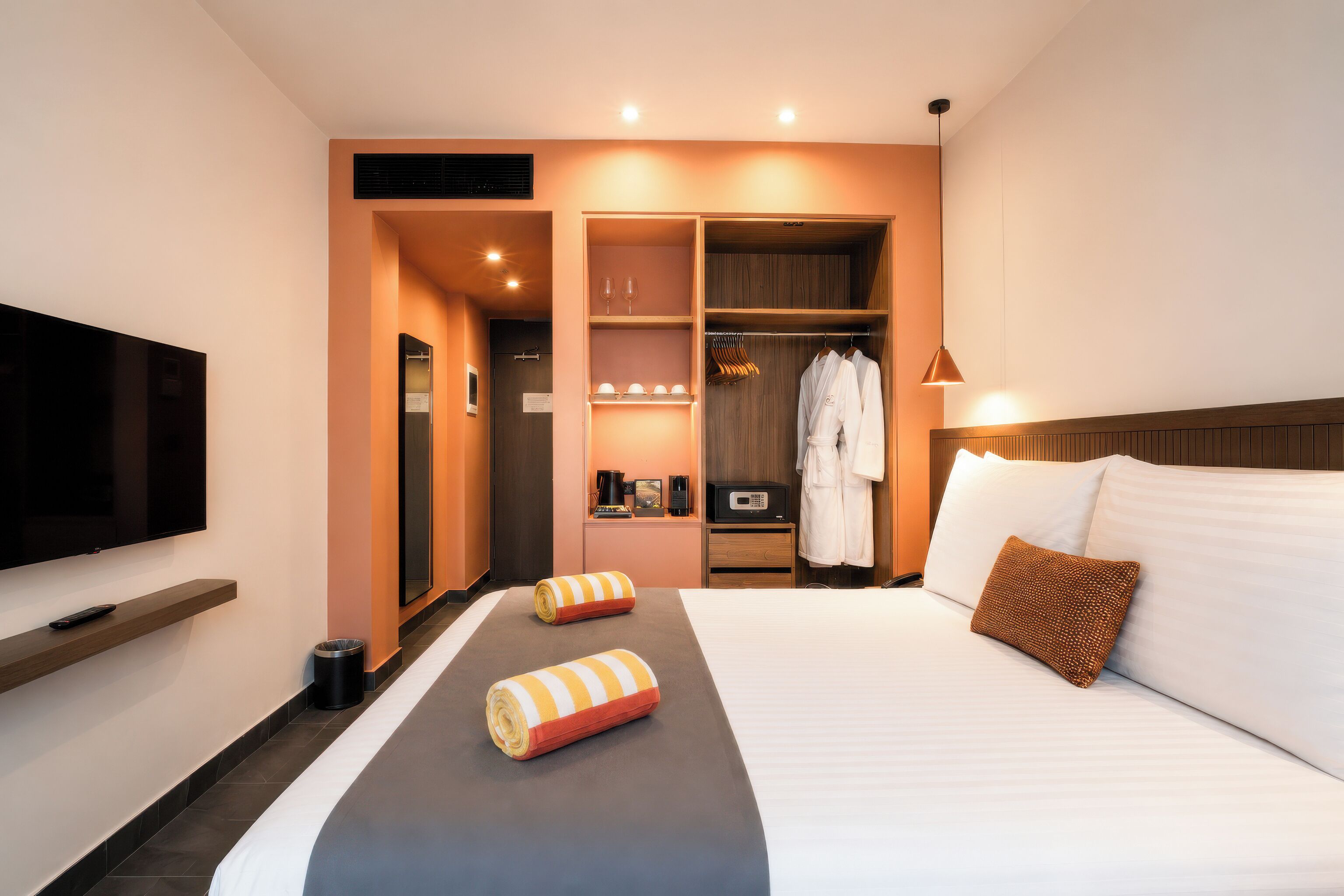 A hotel room with a bed, a TV, a wardrobe, and a mirror.