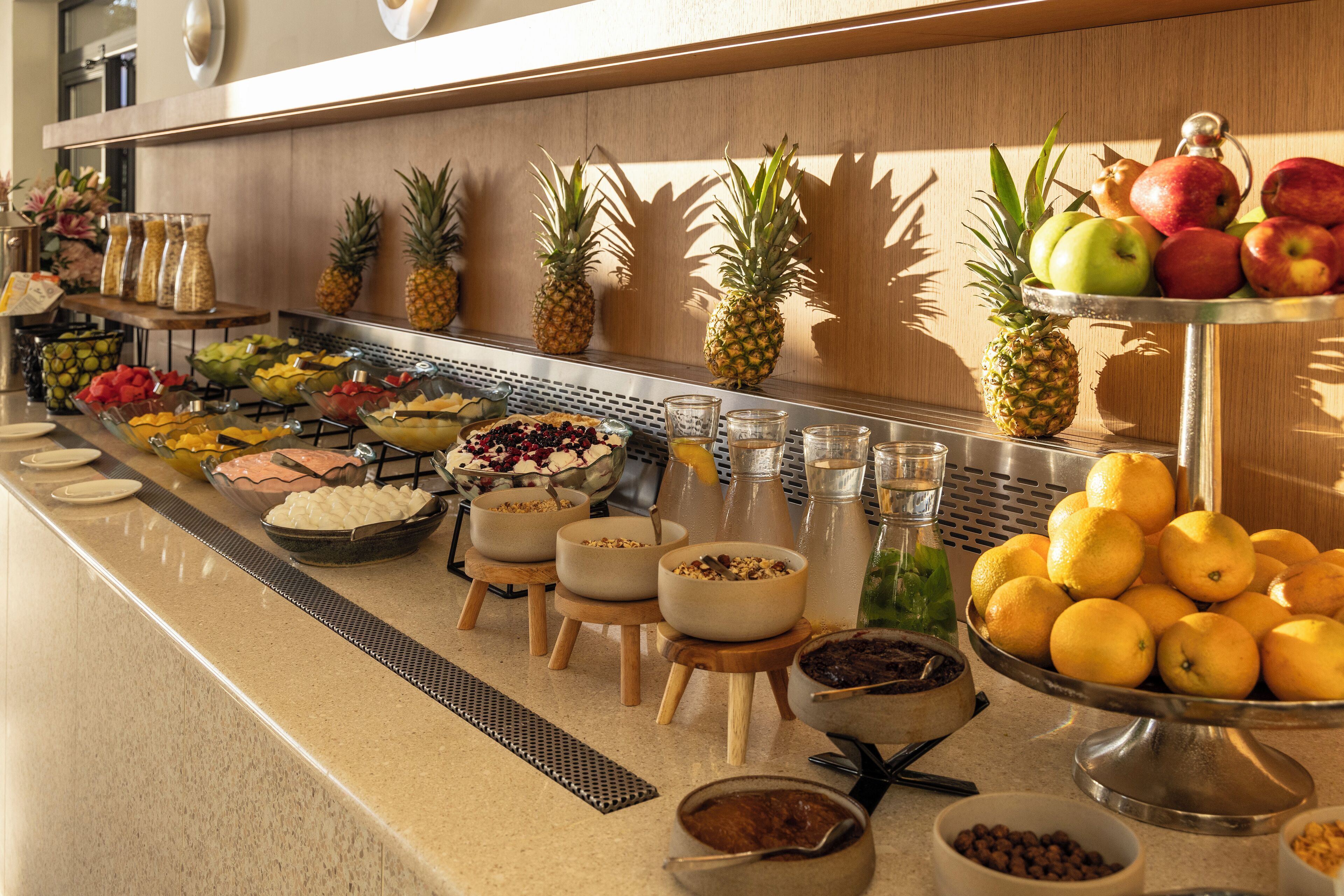 Un buffet con diversi tipi di frutta, contenitori di cibo e salse.
