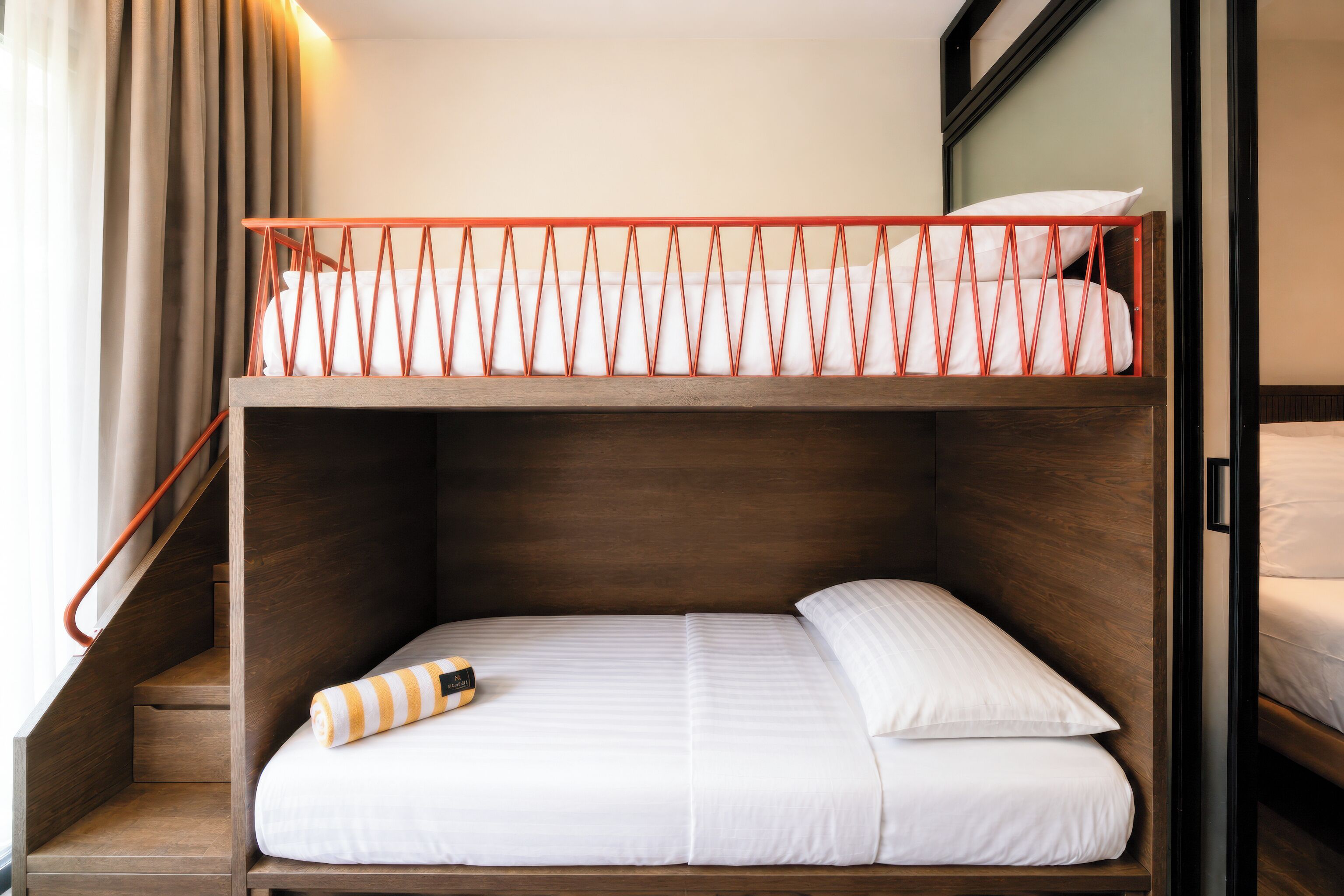 A bunk bed with a wooden frame, a white mattress, and a striped pillow.