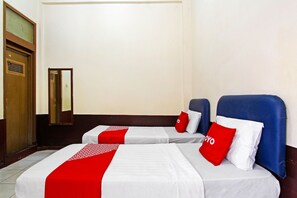 Una habitación de hotel con dos camas, cada una con una colcha y almohadas rojas y blancas.