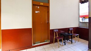 A room with a brown door marked 211, a small table with two chairs, and a window with a red awning. - Hotel O Mutiara (Magelang)