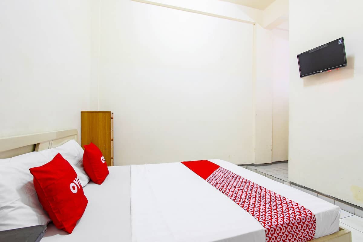Ein Hotelzimmer mit einem Bett, einem an der Wand montierten Fernseher und einer Tür.