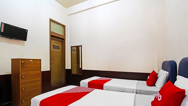 A hotel room with two beds, a wooden dresser, a television, and a mirror. - Hotel O Mutiara (Magelang)