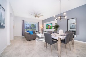 A modern living room with a sofa, coffee table, and dining area with chairs and a table.