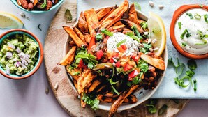 A plate of nachos topped with cheese, jalapeños, and sour cream, accompanied by guacamole and a side of salsa. - Roomshala 111 Cosy Nook (New Delhi)