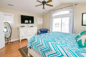 A bedroom with a bed, a television, a dresser, a chair, and a window with a view. - Sol Mate - 5BR 2nd Row Home with Ocean Views, Pool, Hot Tub & Pet Friendly! (North Topsail Beach)