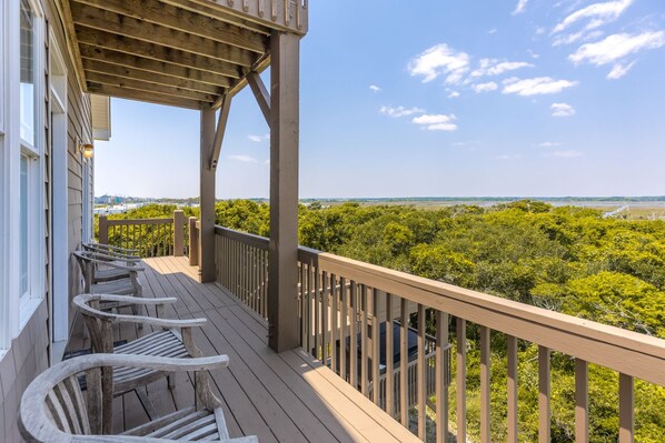 A wooden deck with a railing, overlooking a lush green landscape.
