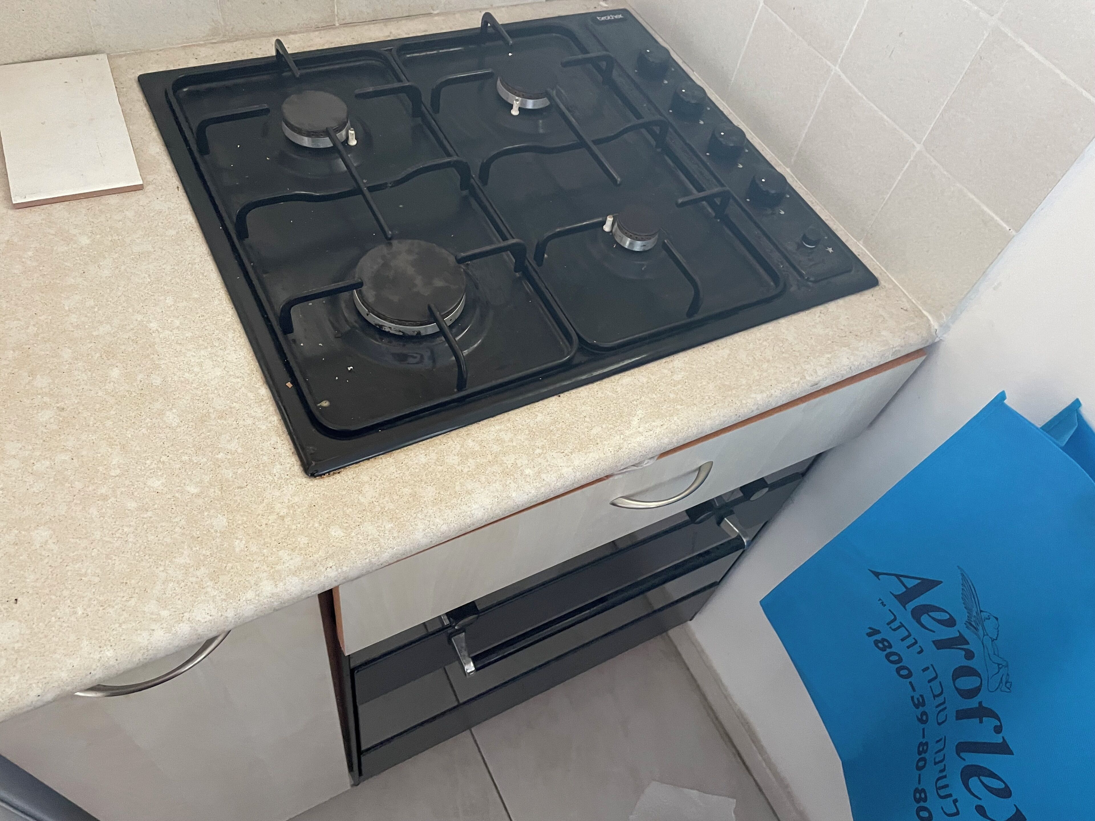 A kitchen with a black stove, a white countertop, and a blue folder.